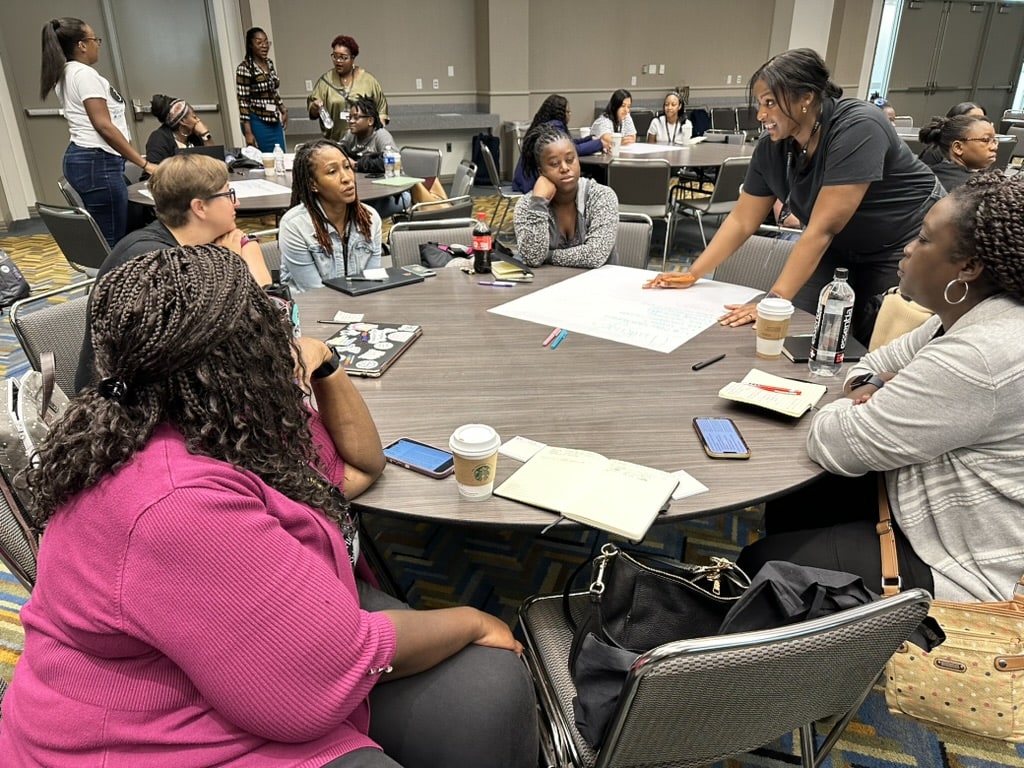 Group of women sitting around a round conference table working on a project