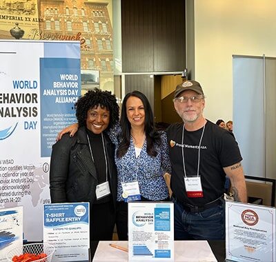 Three people standing behind a conference table